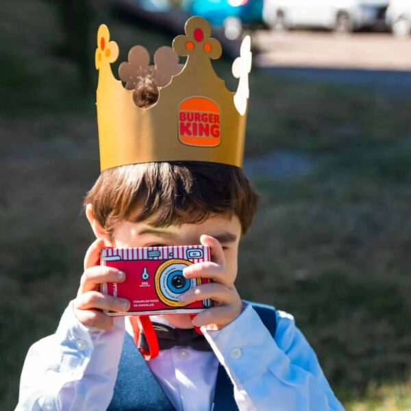 burger king, halloween toy, Young boy with Burger King crown using paper camera outside on a sunny day.