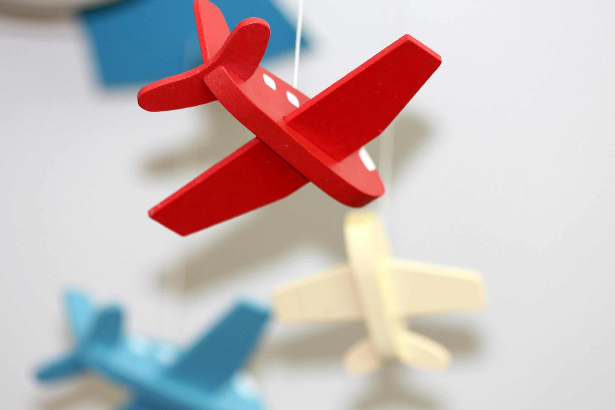 flying, young children, A close-up of colorful wooden airplane toys in a mobile, perfect for nursery décor.