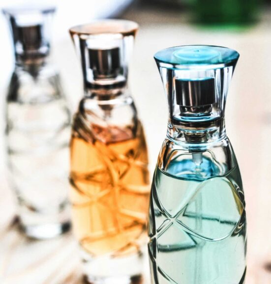 unique fall fragrances, Artistic shot of elegant perfume bottles with colorful liquids on a wooden surface.