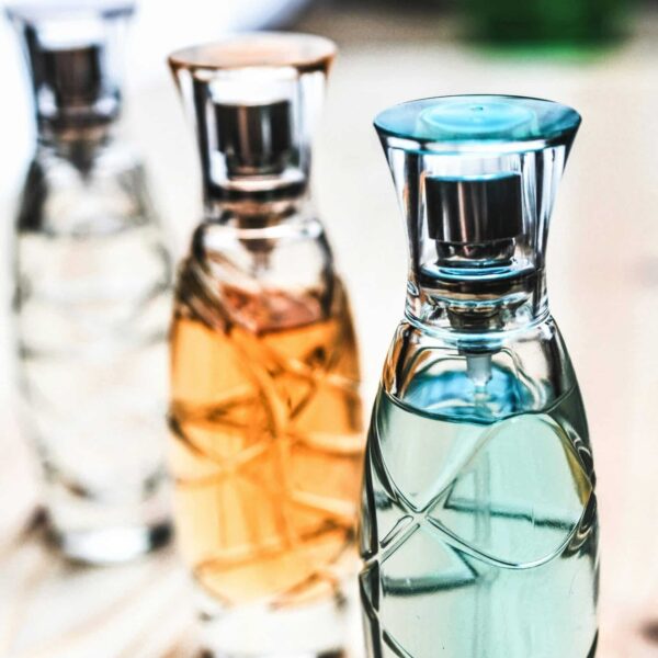 unique fall fragrances, Artistic shot of elegant perfume bottles with colorful liquids on a wooden surface.