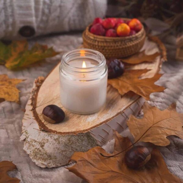 Warm autumn scene with candle, leaves, chestnuts, and cozy textures.