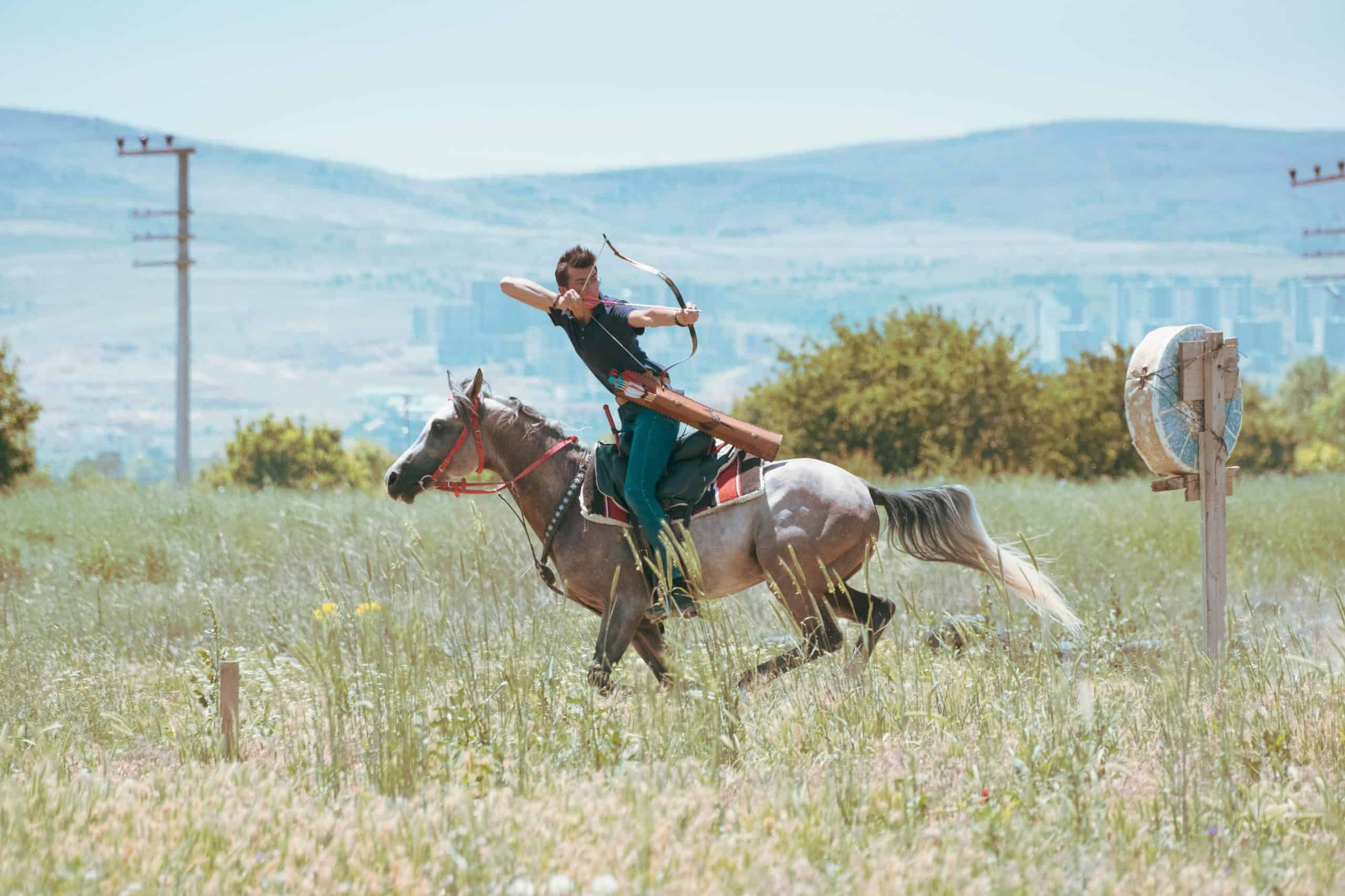A horseback archer practicing in a lush green field in Konya, Türkiye.
