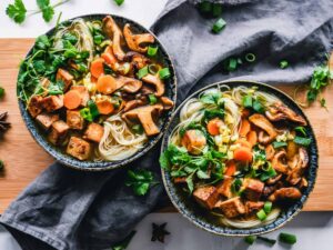 A vibrant noodle bowl with tofu, mushrooms, and fresh vegetables, perfect for a healthy meal. vegan, vegetarian, protein,