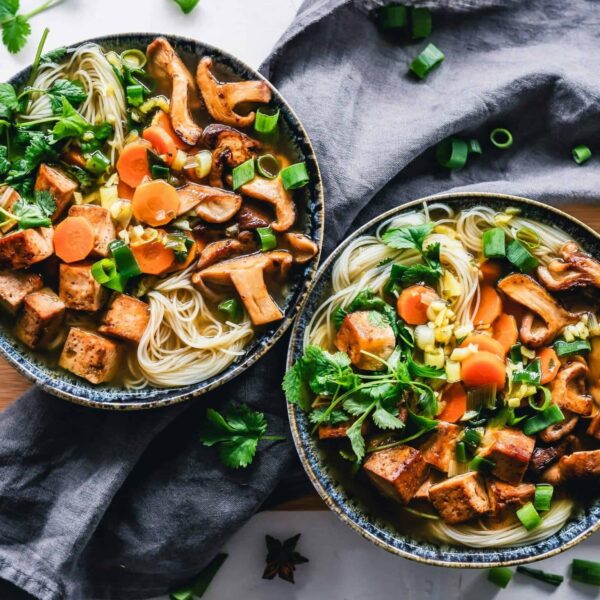 A vibrant noodle bowl with tofu, mushrooms, and fresh vegetables, perfect for a healthy meal. vegan, vegetarian, protein,