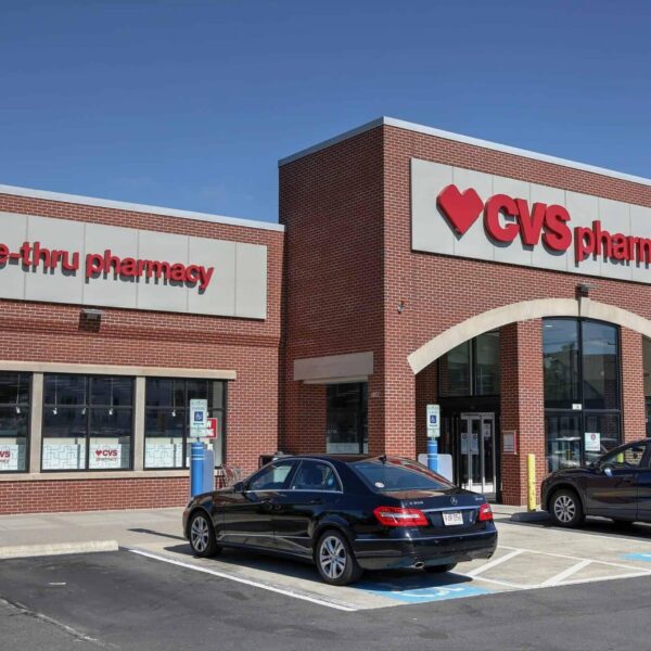 CVS Pharmacy storefront with drive-thru and parked cars, illustrating the CVS recall involving baby drops, colon cleanser, and ice cream products.