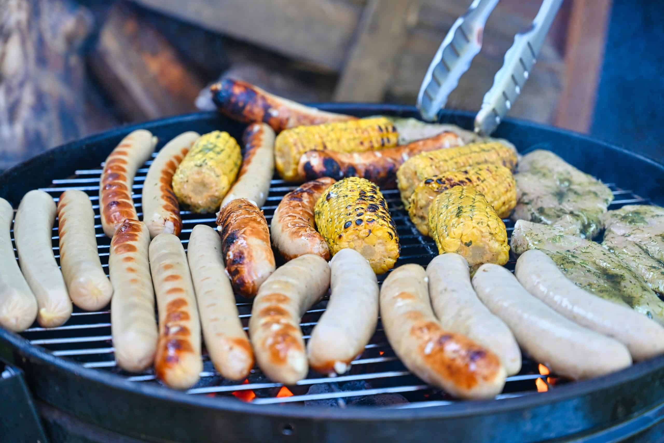 Grilled sausages, corn, and meats on a barbecue grill, perfect for summer cookouts.