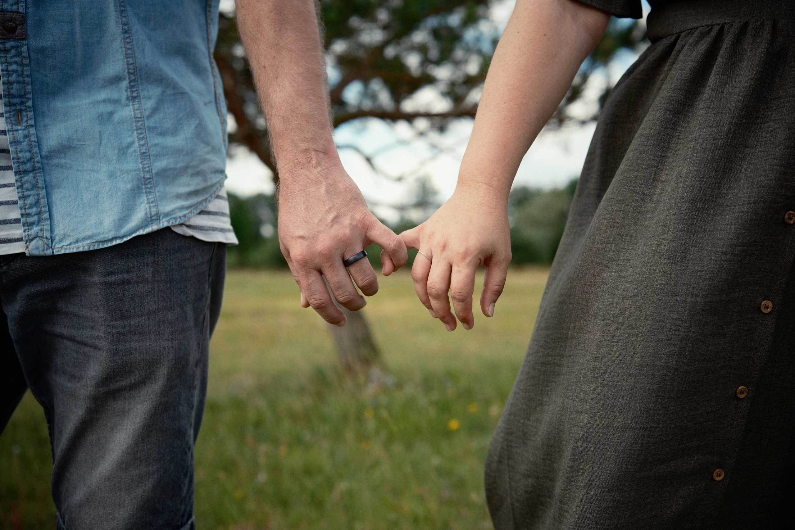 A couple holding hands in a field, symbolizing connection and love, relationship anarchy, modern relationship trend