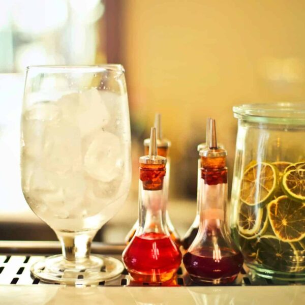 Autumn syrups, Chic cocktail bar setup featuring glassware, citrus slices, and colorful syrups for a refreshing drink experience.