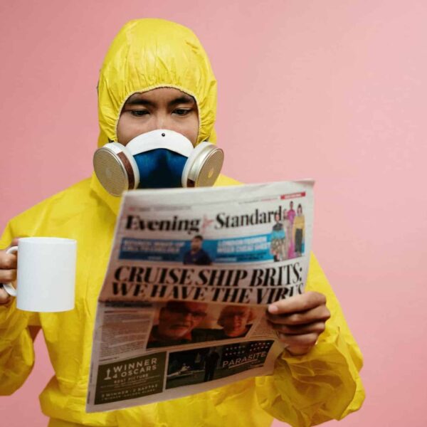 CDC, food poisoning, Person in yellow protective suit reading a newspaper with a mug.