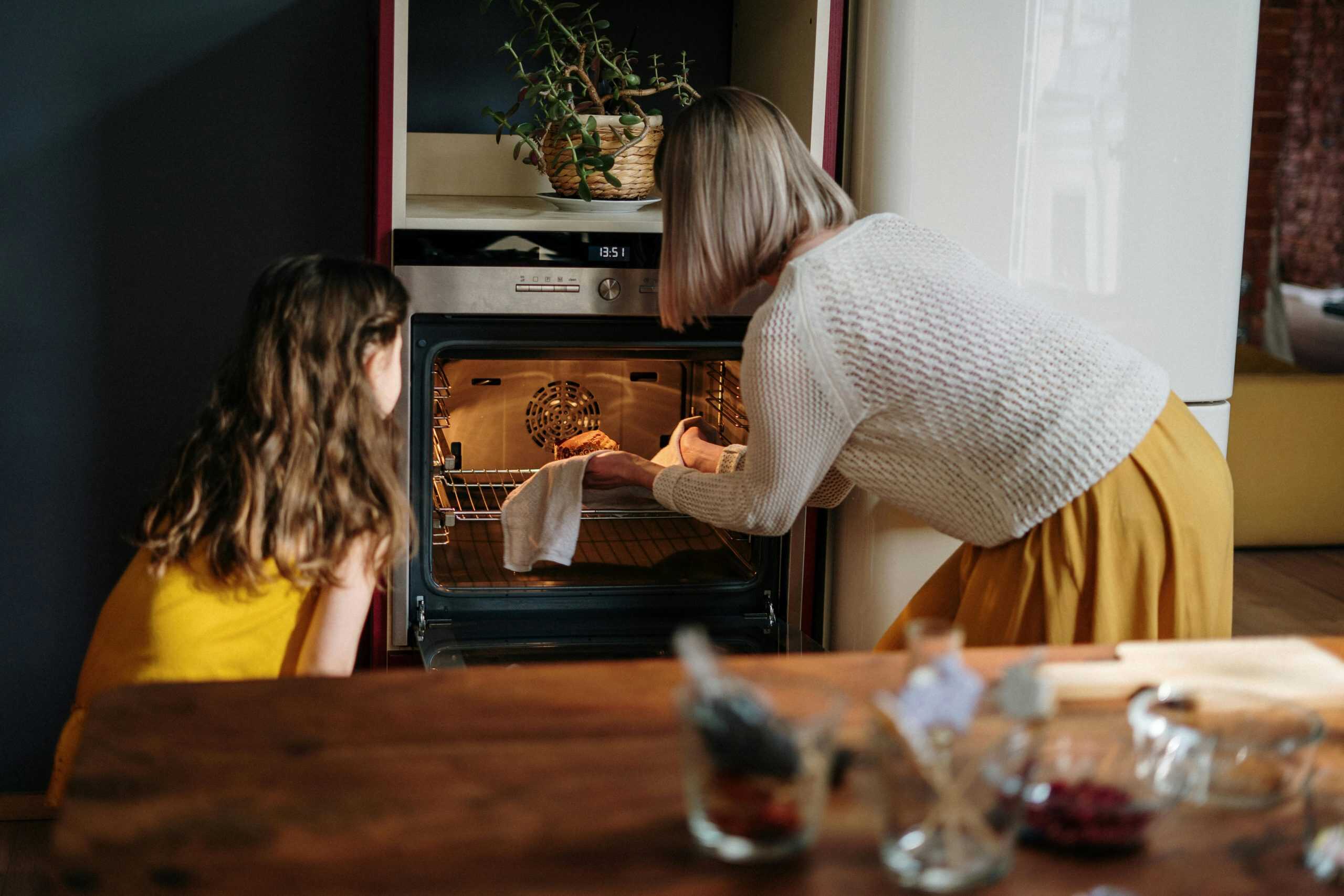 A mother and daughter baking a cake in a cozy kitchen setting, enhancing family time. air fryer vs oven, cooking, better options