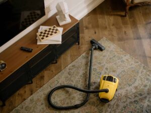 Fall deep cleaning. Warm living room scene featuring a yellow vacuum on a floral carpet with a vintage vibe.