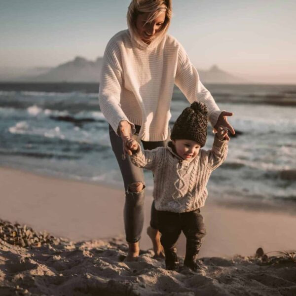 This photograph features a woman and a child enjoying the beach. East Coast beach town vacations can be fun in fall.