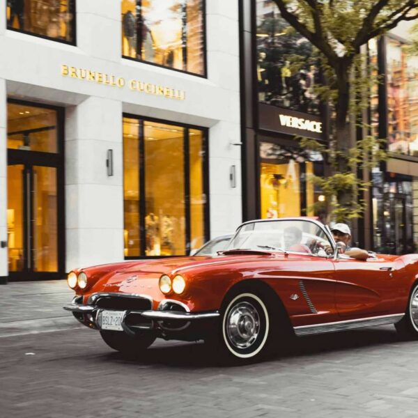 Chevy Corvette Vintage red Chevrolet Corvette convertible driving past luxury shops in Toronto.