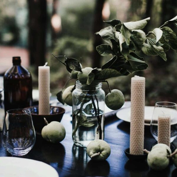 diy, autumn, A rustic table setting outdoors with candles, green apples, and leafy branches creating a serene ambiance.