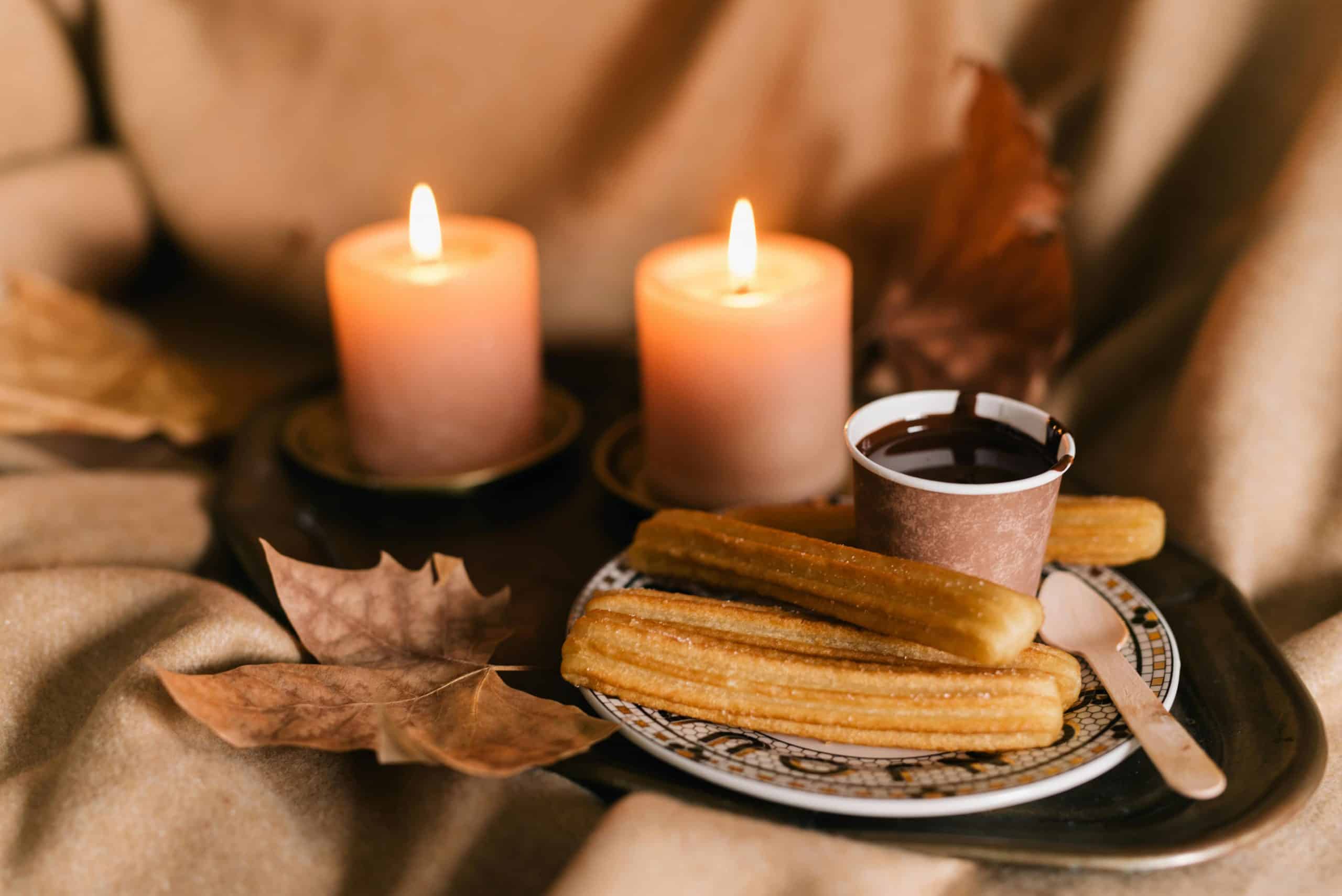 Warm churros and chocolate surrounded by lit candles and autumn leaves, creating a cozy fall atmosphere. living room