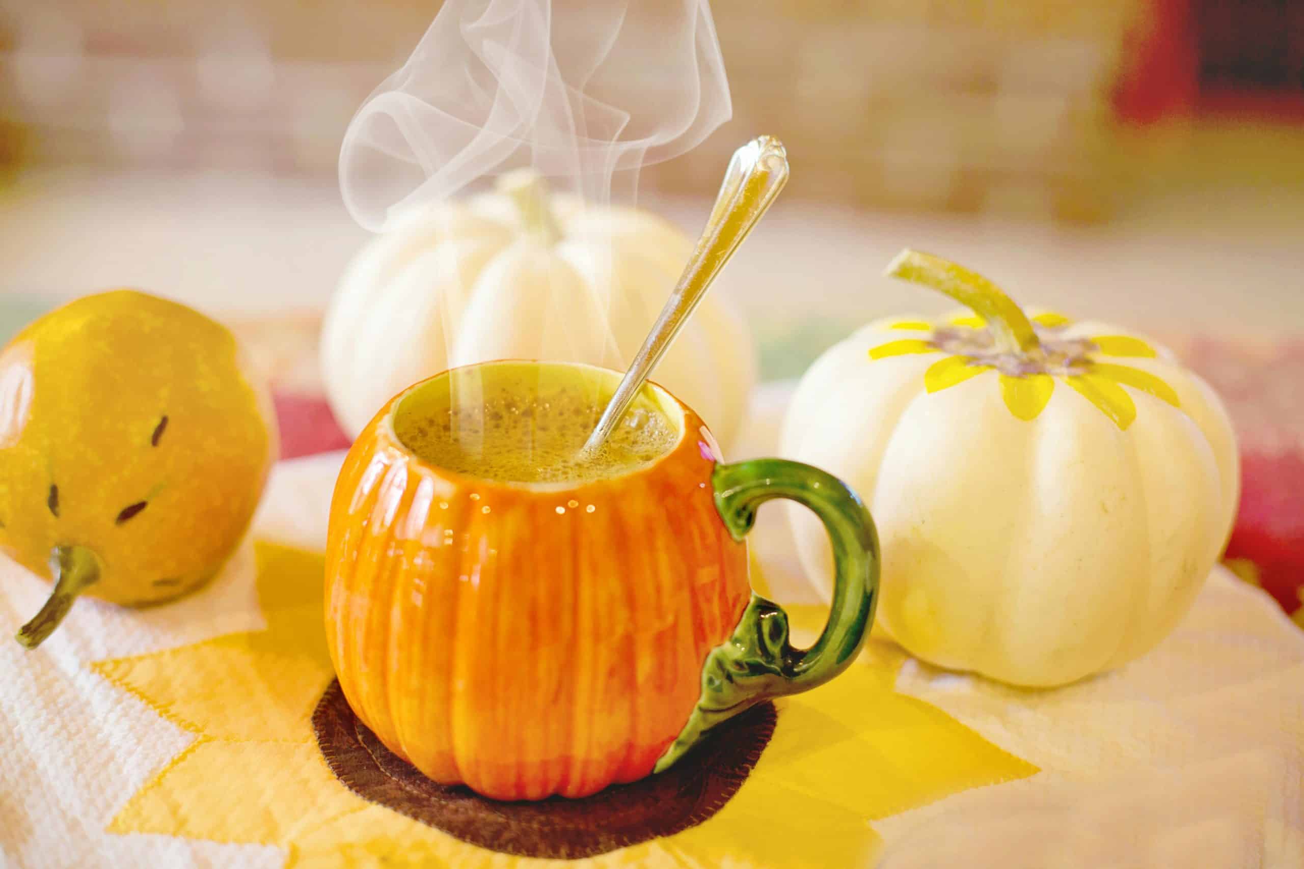 Warm pumpkin spice latte in a pumpkin-shaped mug, perfect for autumn vibes.