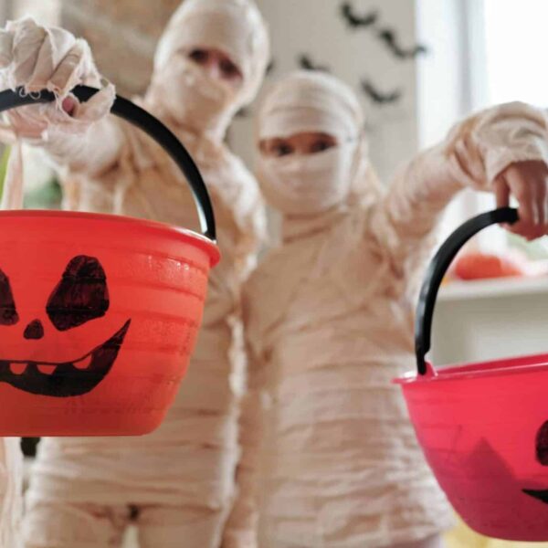 Halloween Candy, Reese's, Two kids dressed as mummies holding jack-o-lantern buckets for Halloween indoors.