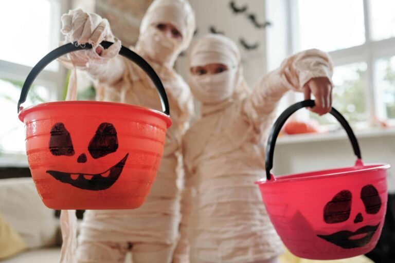 Halloween Candy, Reese's, Two kids dressed as mummies holding jack-o-lantern buckets for Halloween indoors.
