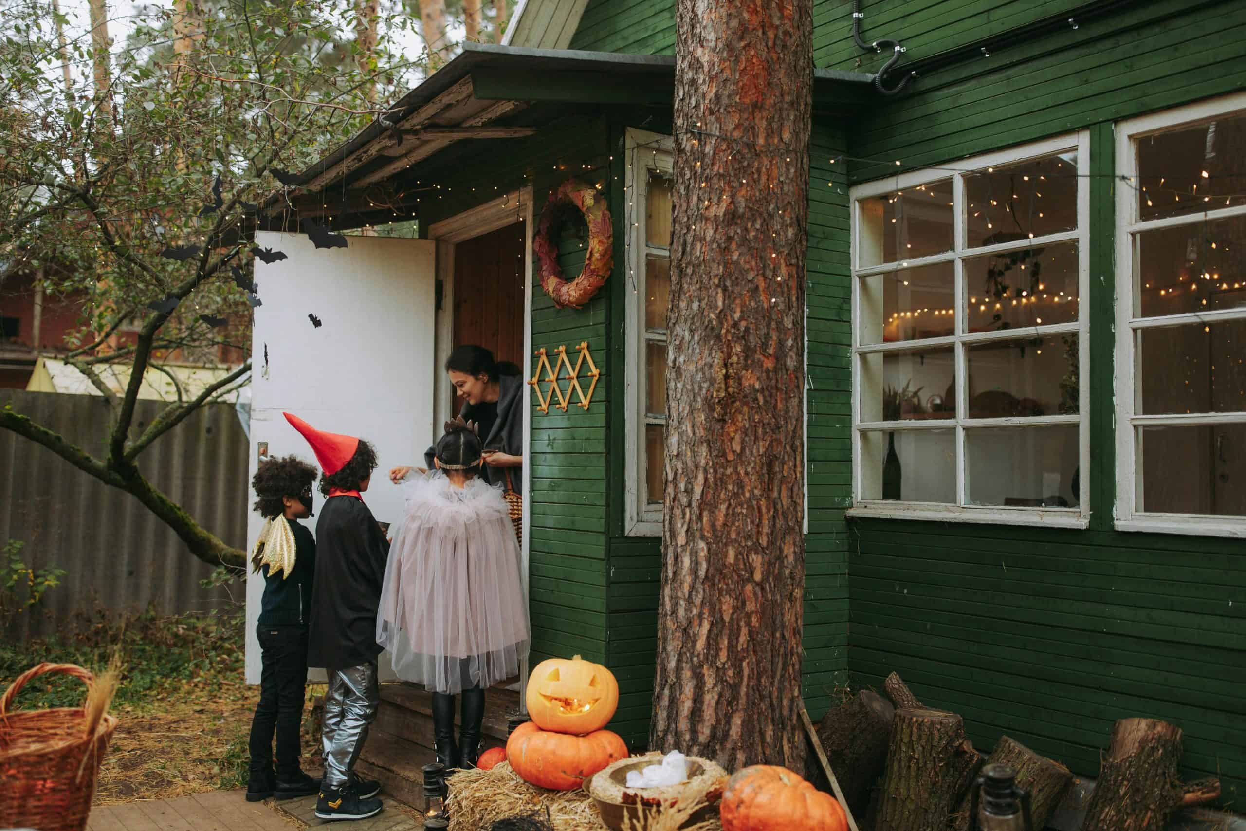 Children in costumes trick-or-treating at a decorated house during Halloween night.