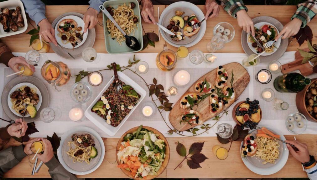 Dinner Party, Fall theme, Overhead shot of a vibrant dining table setup with pasta, salads, and decorative candles, capturing a festive gathering.