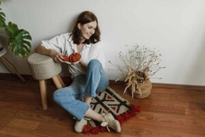 This is a photograph of a woman sitting on the floor. You can declutter your space before hosting fall holiday visitors.