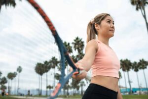 Active woman playing tennis in park with palm trees surrounding tenniscore