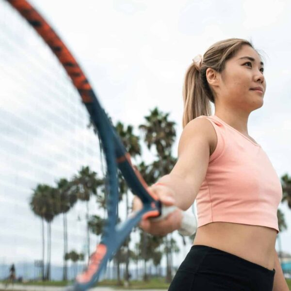 Active woman playing tennis in park with palm trees surrounding tenniscore