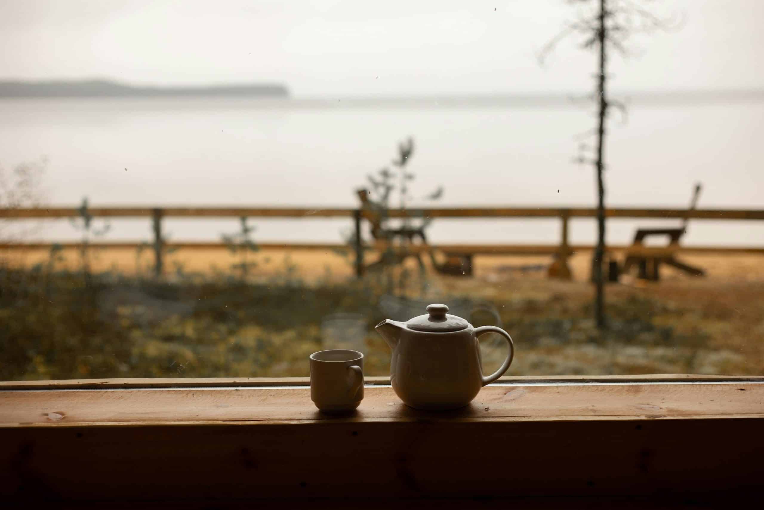 Serene outdoor view from a window with a teapot and mug on a wooden ledge. Perfect serenity.