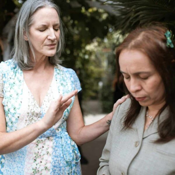 Two women in a peaceful prayer moment, sharing spiritual connection outdoors, emotional intelligence, The Bible