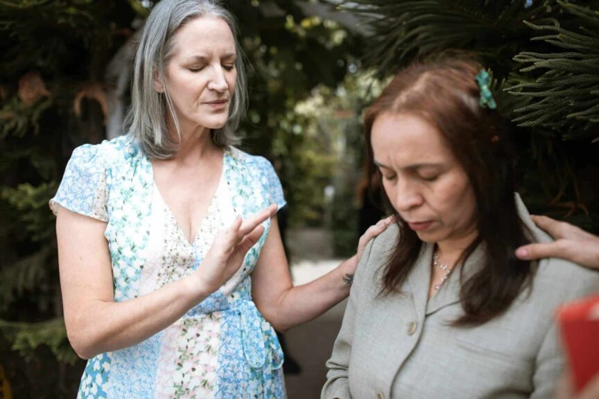 Two women in a peaceful prayer moment, sharing spiritual connection outdoors, emotional intelligence, The Bible