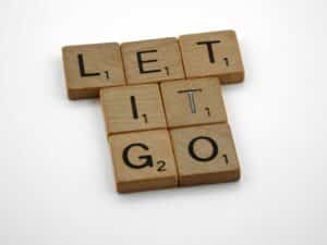 Wooden letter tiles spelling 'Let It Go' on a white surface for inspiration. Fall change.