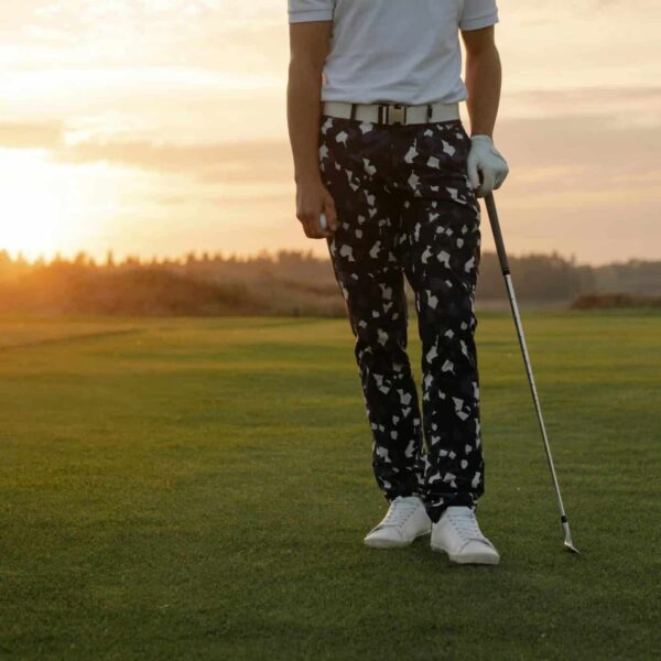 Golfer holding a club on a scenic golf course at sunset, exuding professionalism.