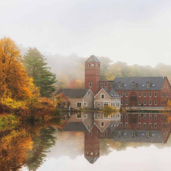 Road trip, Northeast, Serene autumn scene with a historic mansion and vibrant foliage reflected on still water.