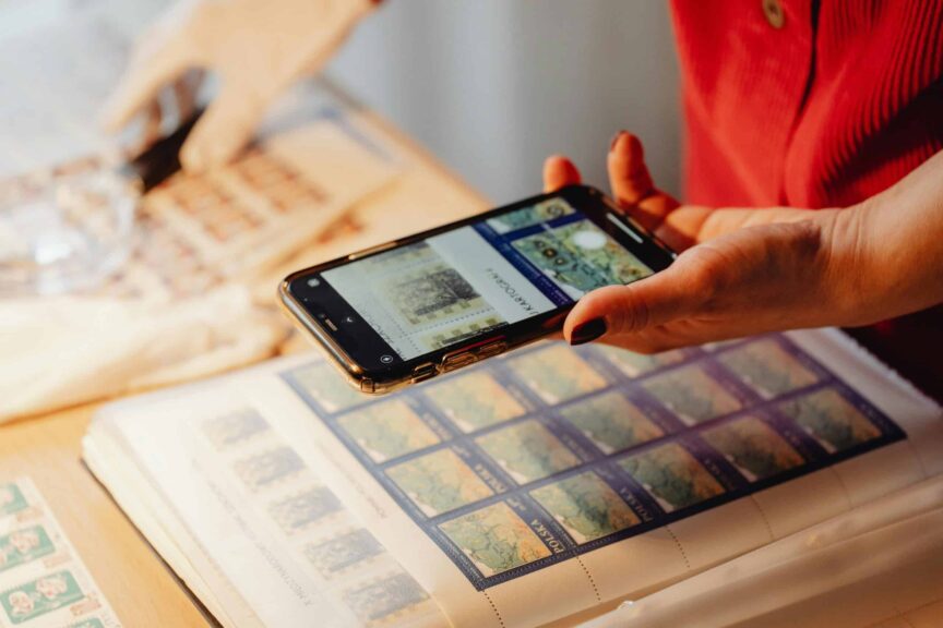 Individual photographing a stamp collection using a smartphone for cataloging. Internet archive