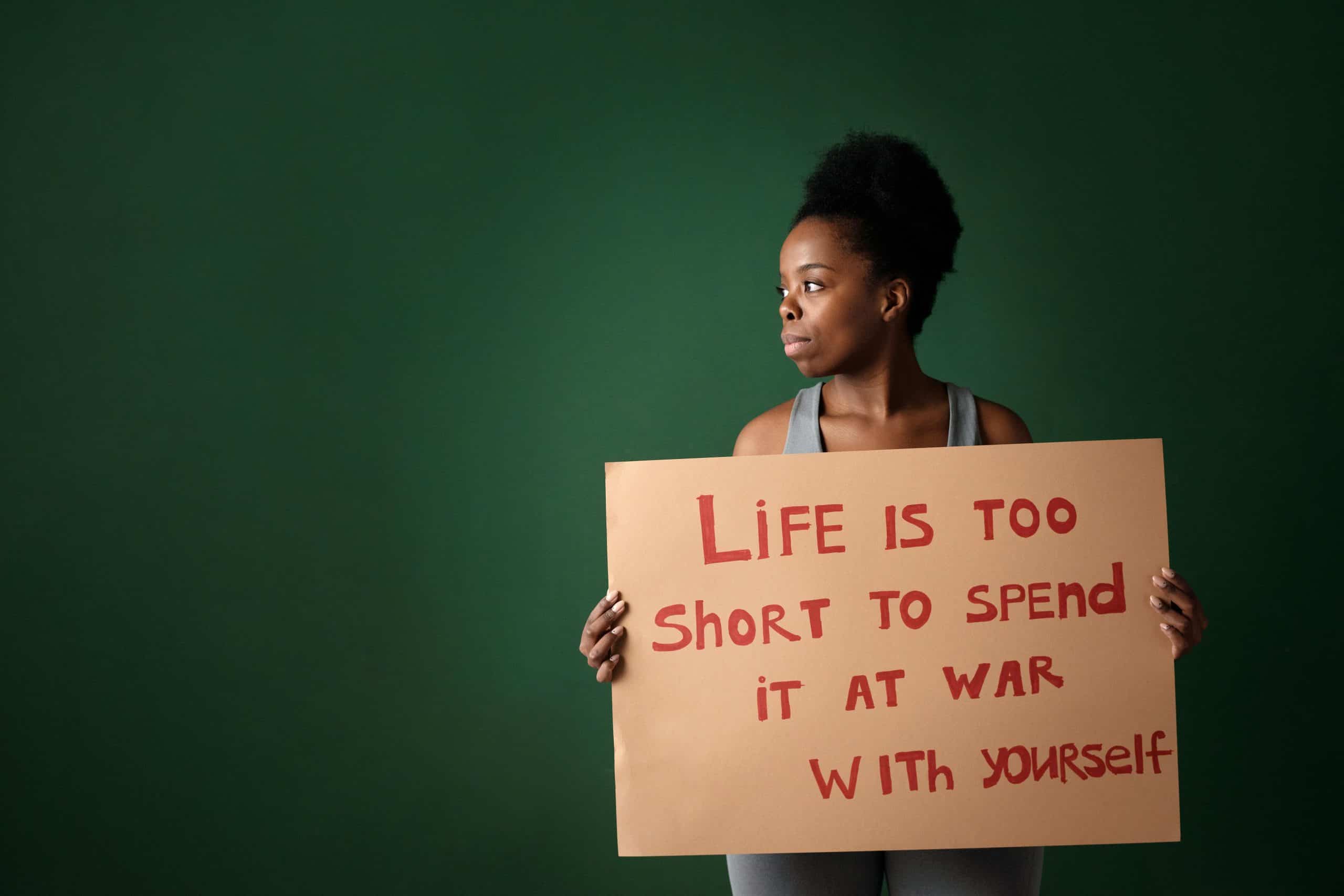 African American woman holding a sign with a motivational message in a studio setting.