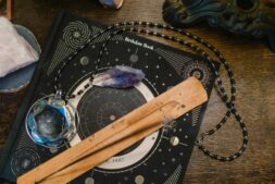 Astrology-themed flat lay featuring a birthdate book, crystals, and necklace on a wooden surface. elemental astrology
