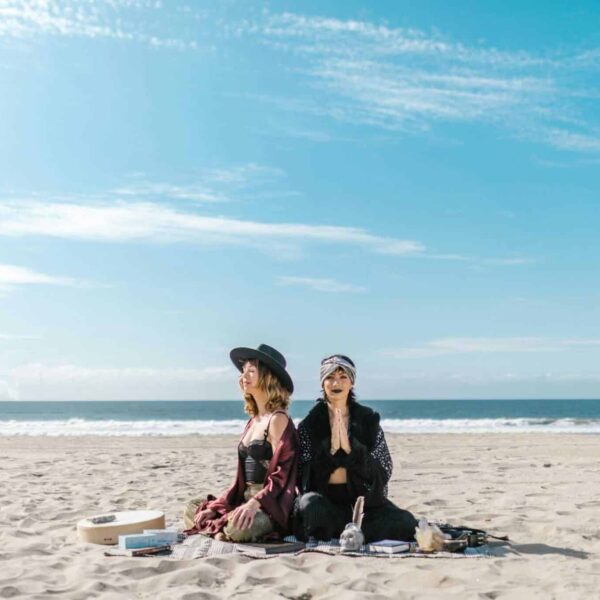 Manifestation, Women practicing meditation and crystal healing on a sunny beach.