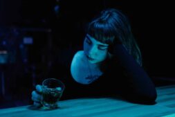 A woman with eyes closed holds a drink at a dim bar. Moody nightlife scene. nonalcoholic drinks
