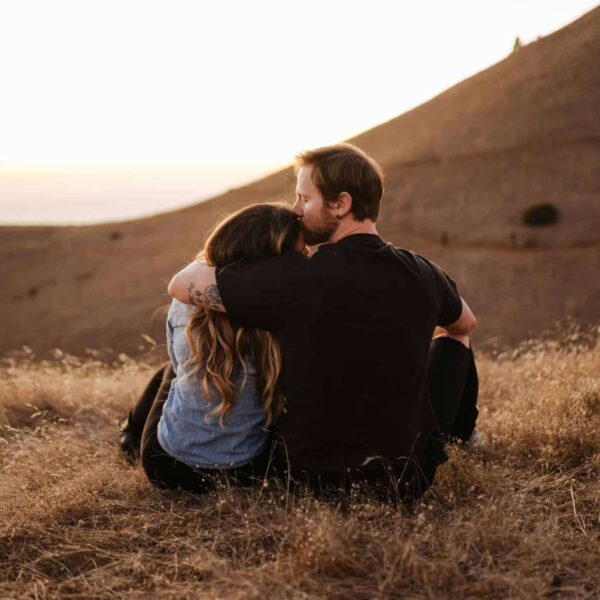 This a photograph of a couple sitting together on a hill. A relationship sabbatical can help a couple from drifting apart.