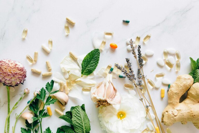 A flatlay of natural herbs, supplements, and flowers on a marble background. creatine
