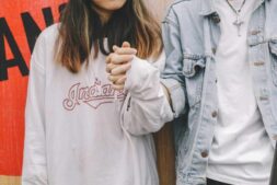 Young couple holding hands in casual attire, symbolizing love and togetherness.