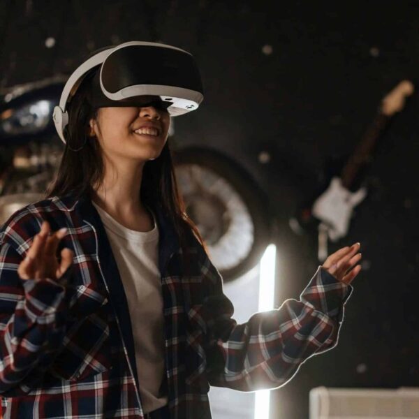 Phygital, Young woman immersed in virtual reality using a VR headset, enjoying a digital world indoors.