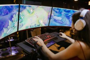 A young woman intently gaming on a multi-screen setup, showcasing vibrant gaming visuals./adult-themed games
