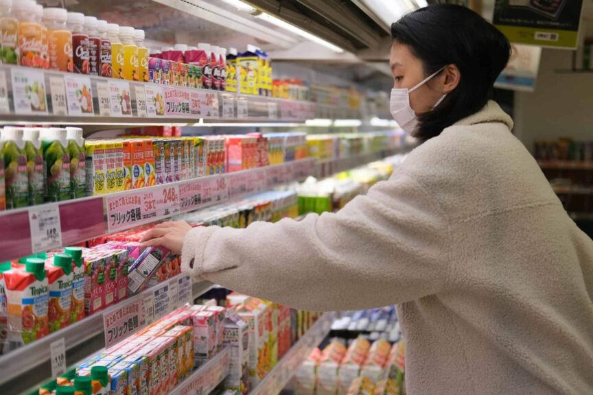 Masked woman shopping for beverages in a supermarket aisle, juice recall, unpasteurized