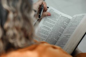 Close-up of a woman reading a Bible with a pen, focused on text. Daily devotion