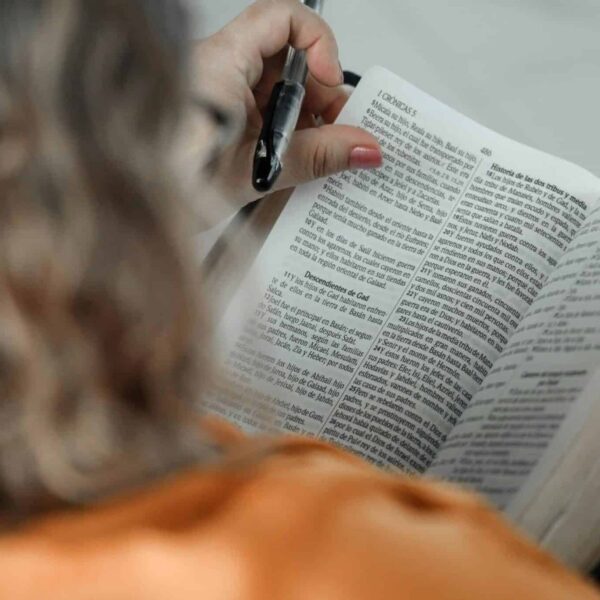 Close-up of a woman reading a Bible with a pen, focused on text. Daily devotion
