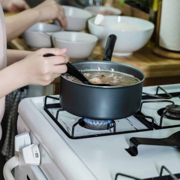 Close-up of a woman stirring soup on a gas stove in a home kitchen. one-pot soup