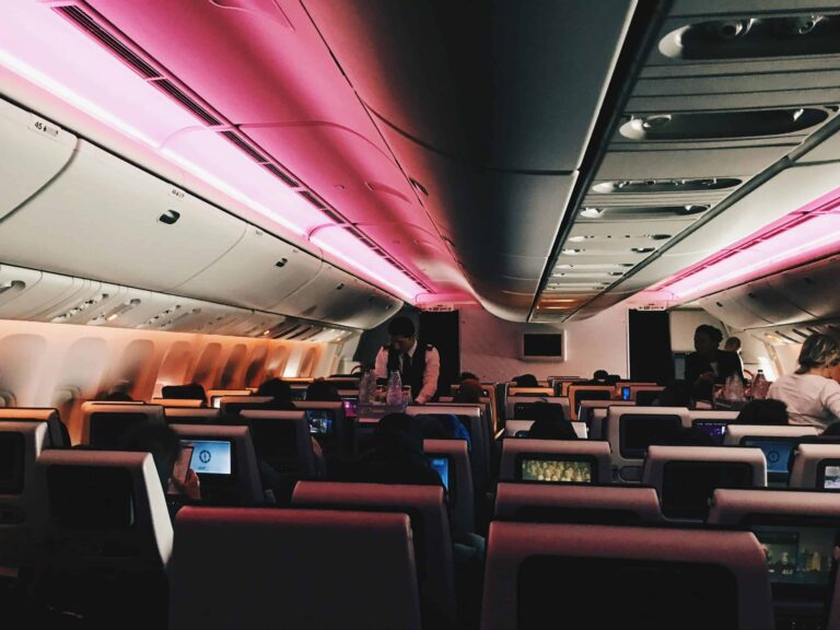 Overhead bin, Interior view of an airplane cabin at night with passengers and ambient lighting.