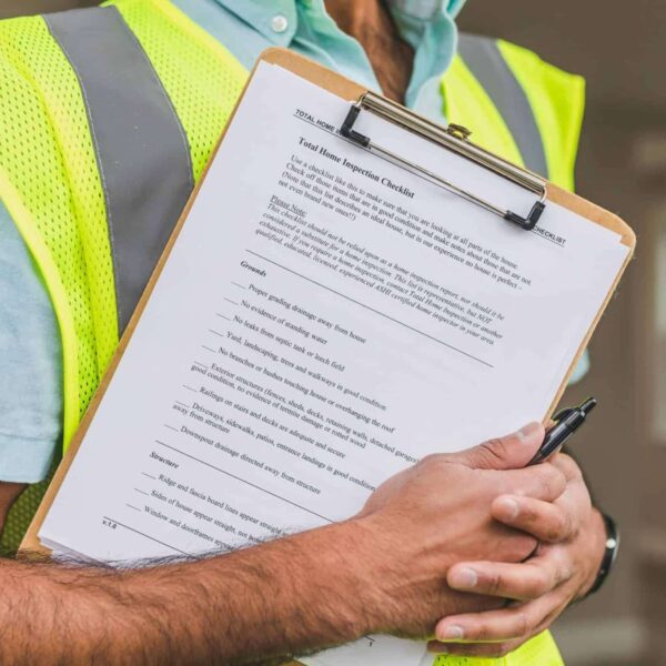 red flags, home inspectors, Close-up of home inspector holding a checklist on a clipboard with a pen.