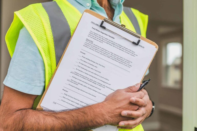 red flags, home inspectors, Close-up of home inspector holding a checklist on a clipboard with a pen.